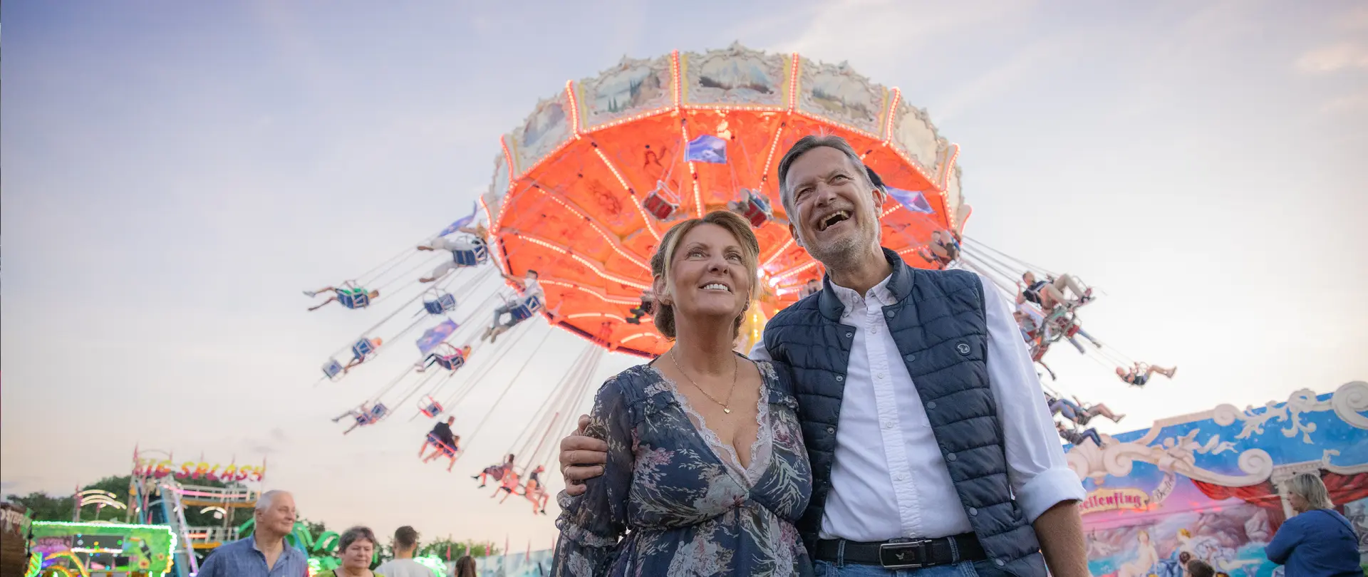 Viehmarktsflair vor dem Kettenkarussell Lachendes Paar steht vor dem Kettenkarussell auf dem Viehmarkt.