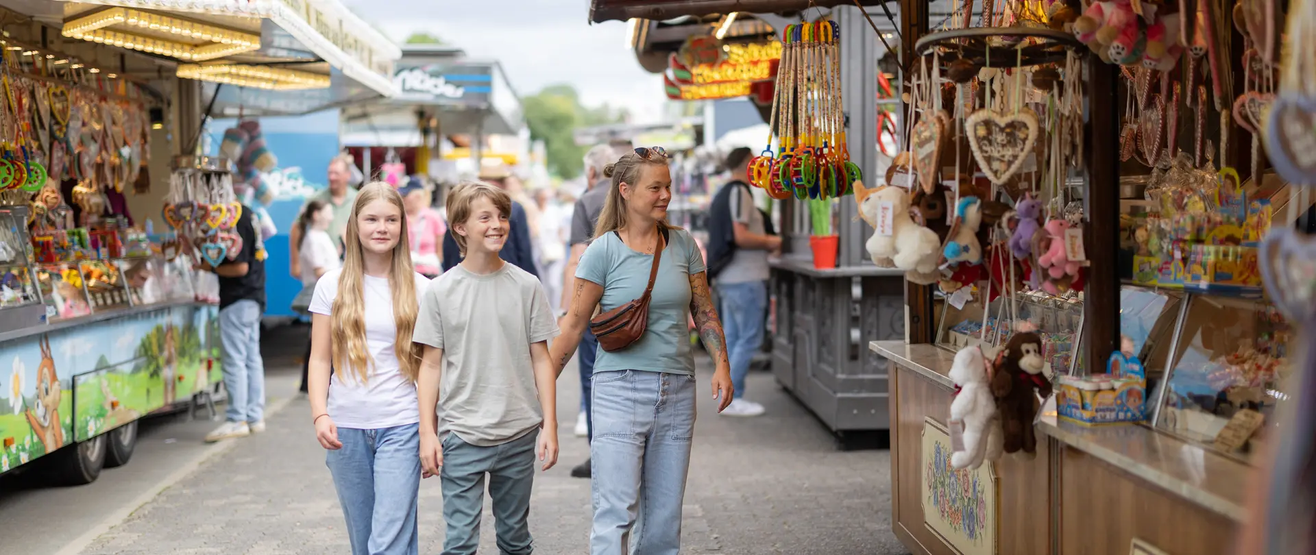 Familie schaut auf dem Viehmarkt sich die Schaustellerstände an.