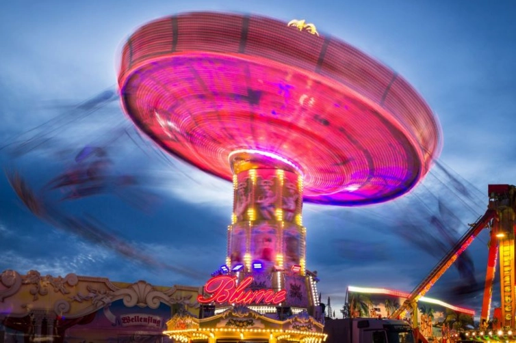 Kettenkarussell bei Nacht Rosa beleuchtetes Kettenkarussell dreht sich bei Einbruch der Dämmerung