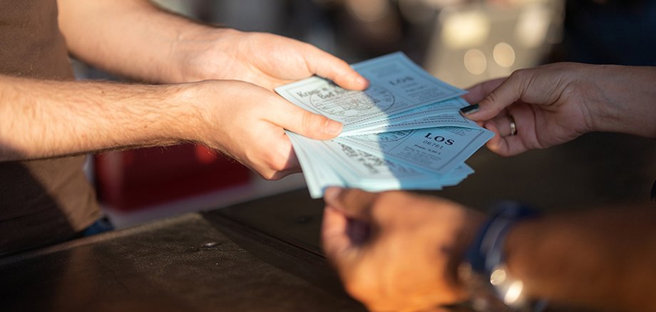 Aufgefächerte Lose der Viehmarktslotterie werden gezogen.