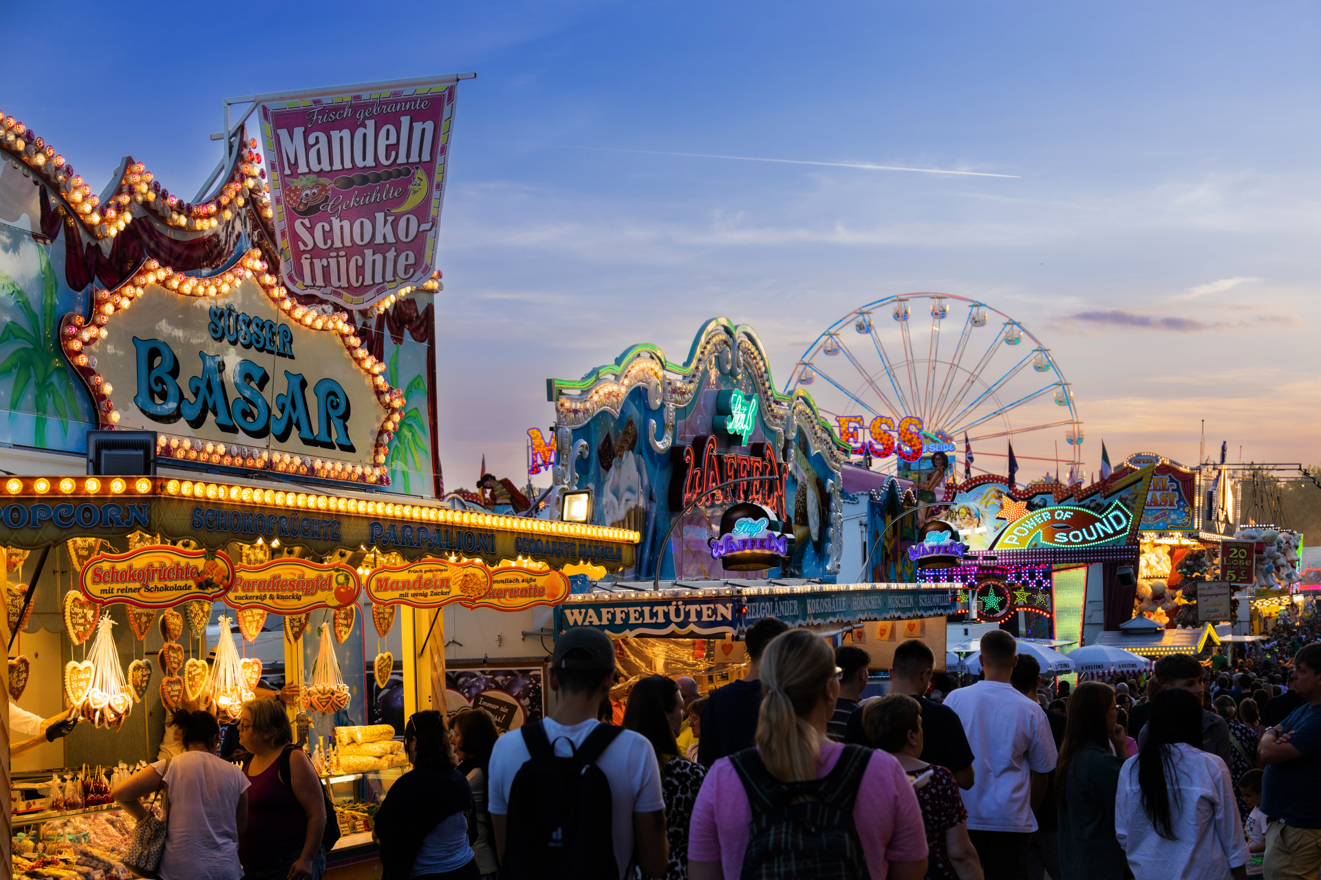 Blick auf den Viehmarkt und insbesondere Essenstände, die rege besucht werden, bei untergehender Sonne.