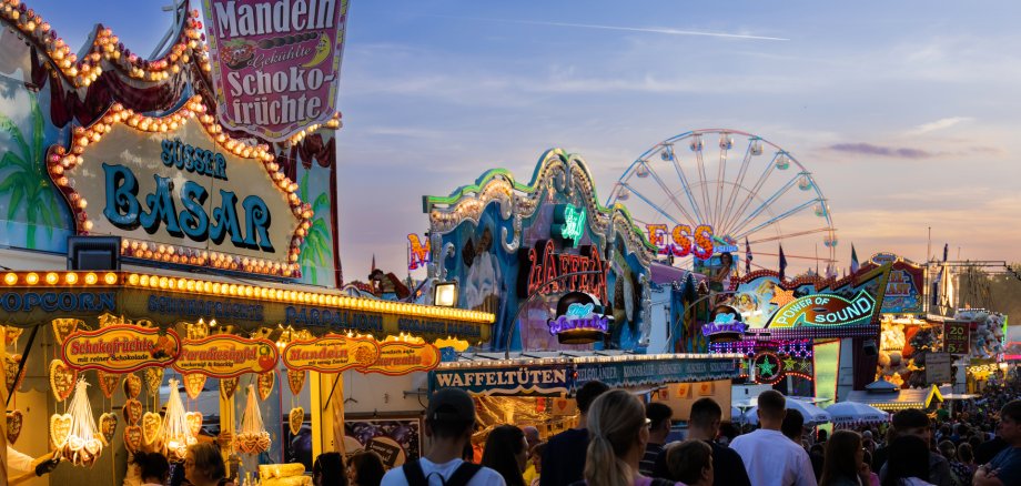 Blick auf den Viehmarkt und insbesondere Essenstände, die rege besucht werden, bei untergehender Sonne.
